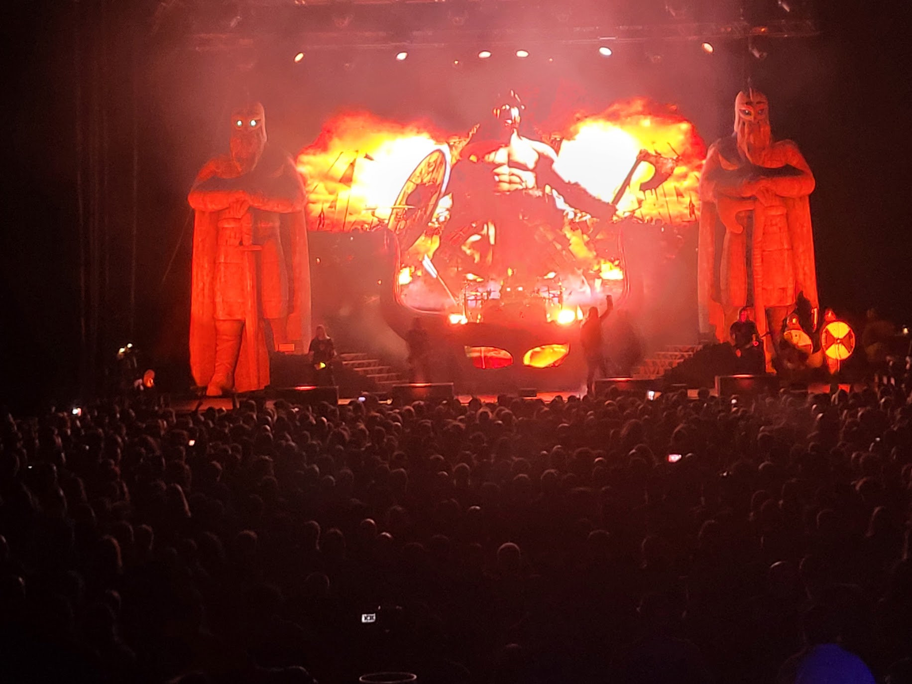 The stage at an Amon Amarth concert. The stage is adorned with red skulls, fire, and barbarian imagery.